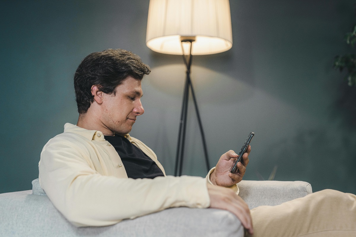 man sitting on a couch, using a smartphone