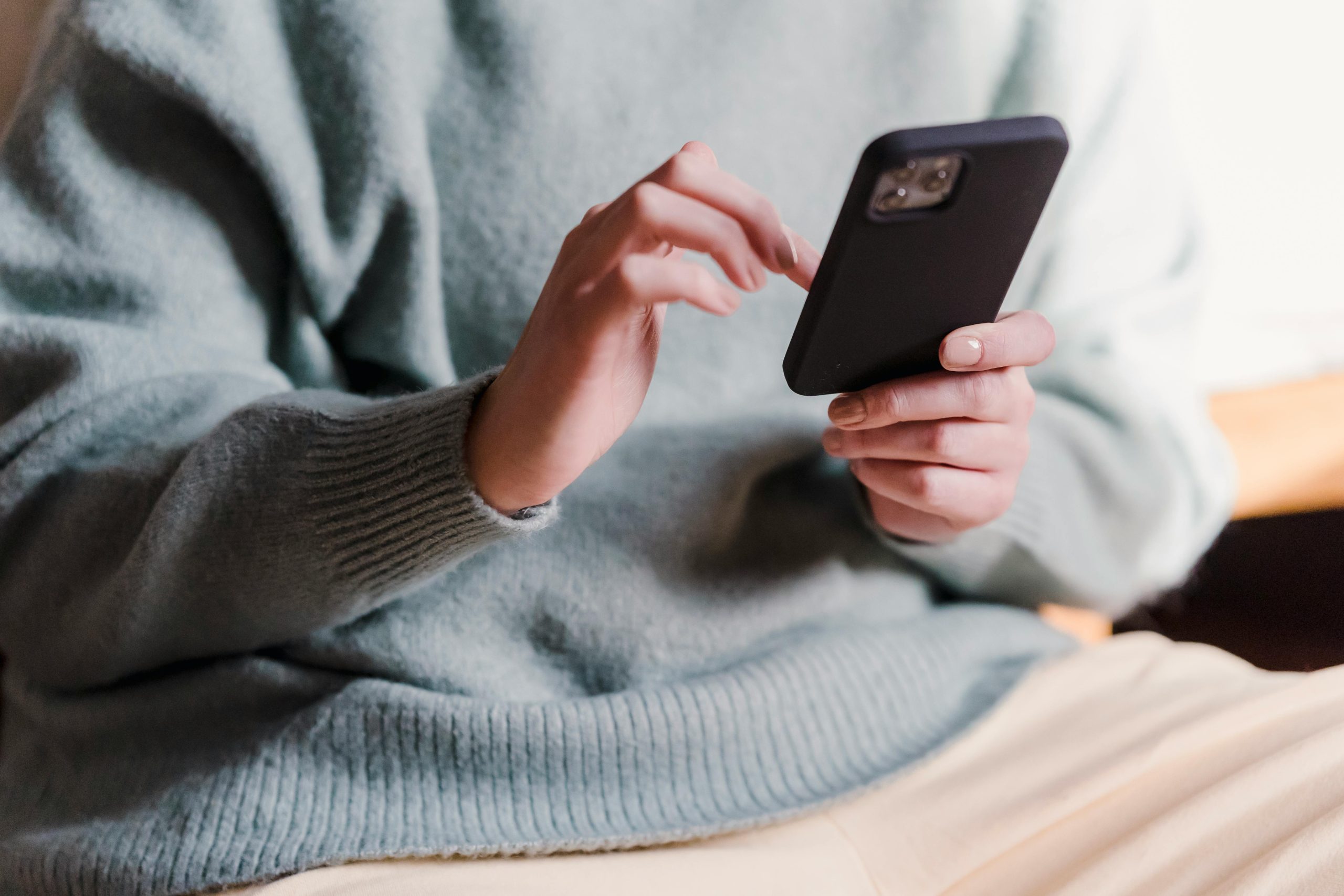 woman in a sweater using a smartphone